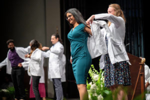 Image of professors putting white coats on students