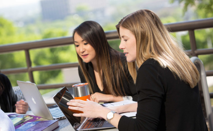 two female students on a laptop at an outdoor table