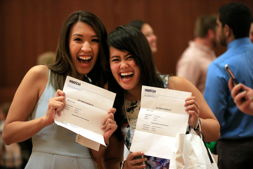 two TCOM students holding up their match letters