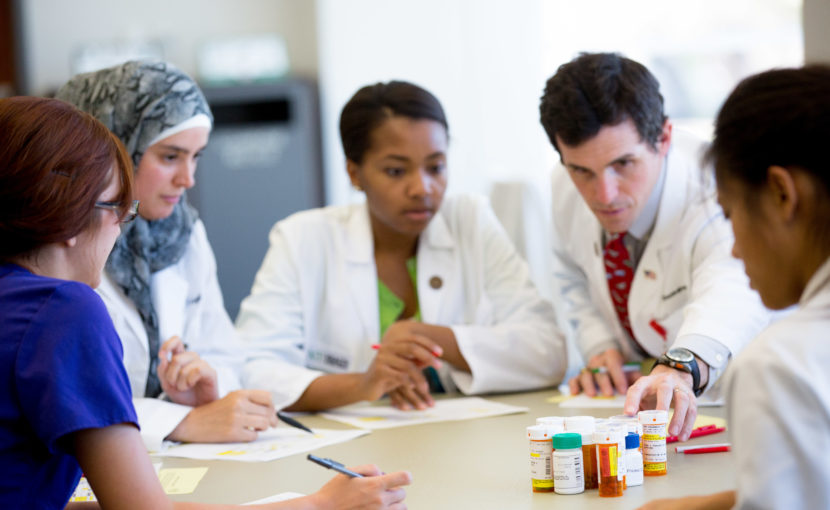 pharmacy students at a table discussing prescription bottles