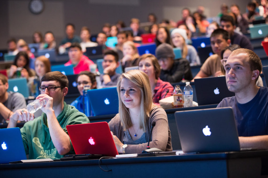 students on laptops in a lecture auditorium