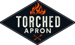 the torched apron logo has illustrated flames over a crossed fork and spatula