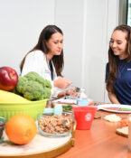 A UNT Health faculty member discusses nutrition with a student, with fresh fruits, vegetables and healthy foods displayed on the table.
