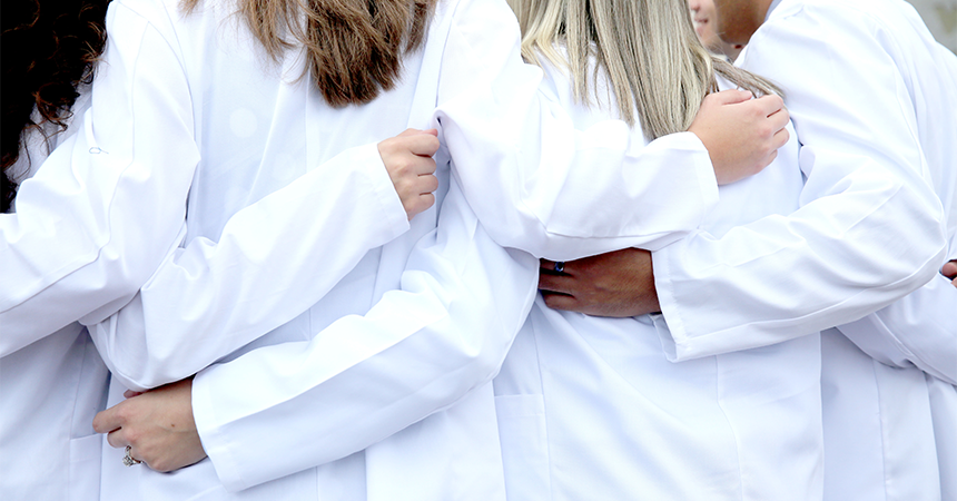 Students wearing white coat with backs turned