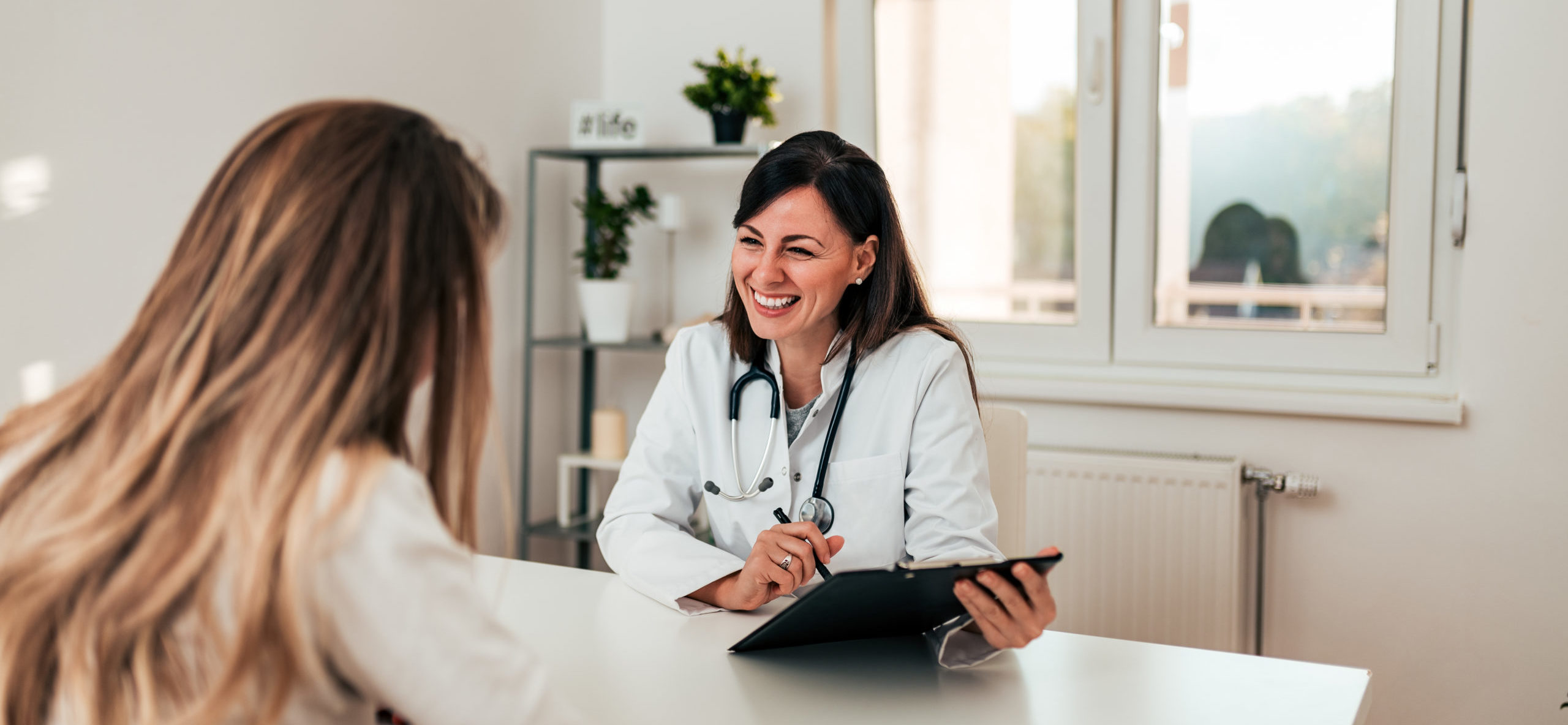 Young Doctor And Patient Talking In The Doctor's Office.