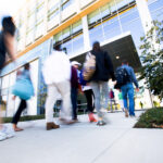 Photograph of students walking into a campus building from outdoors.