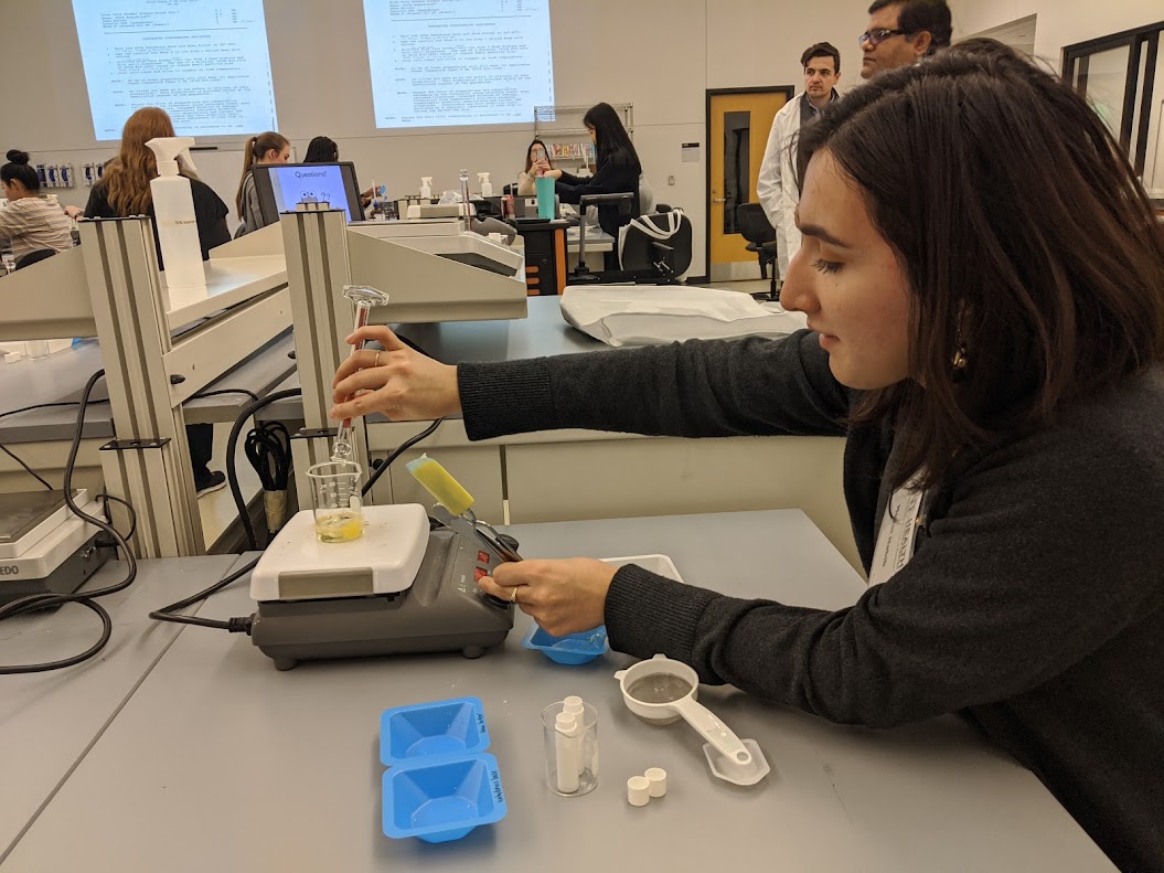 a student using a scale pouring liquids from a graduated cylinder into a flask