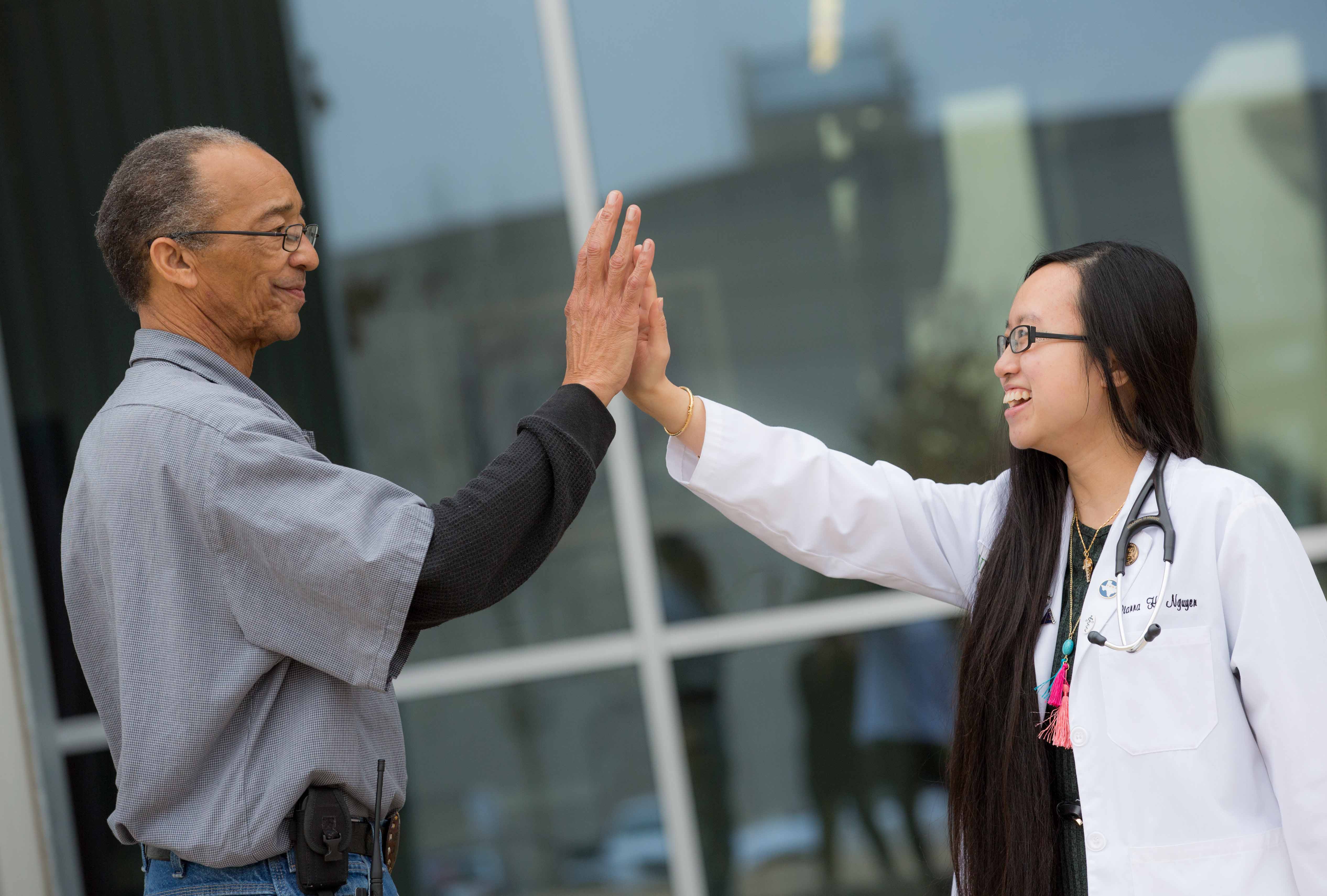 Tcom Student Dianna Nguyen And Employee Larry Clark High Five.